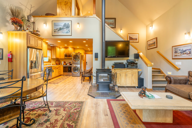 Merry Canyon cabin interior with a vaulted ceiling, wood stove, and open kitchen