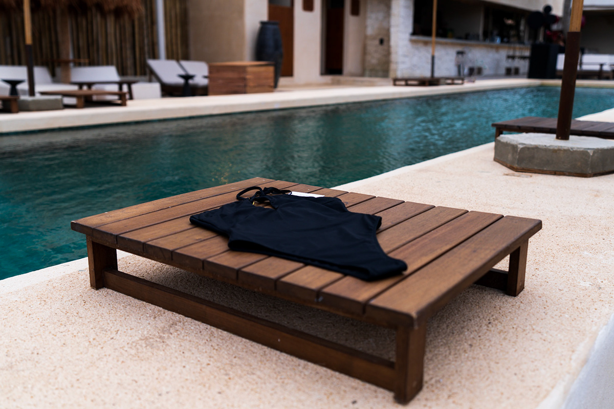 Black swimwear arranged on a wooden poolside table — Balabambas Beach Club