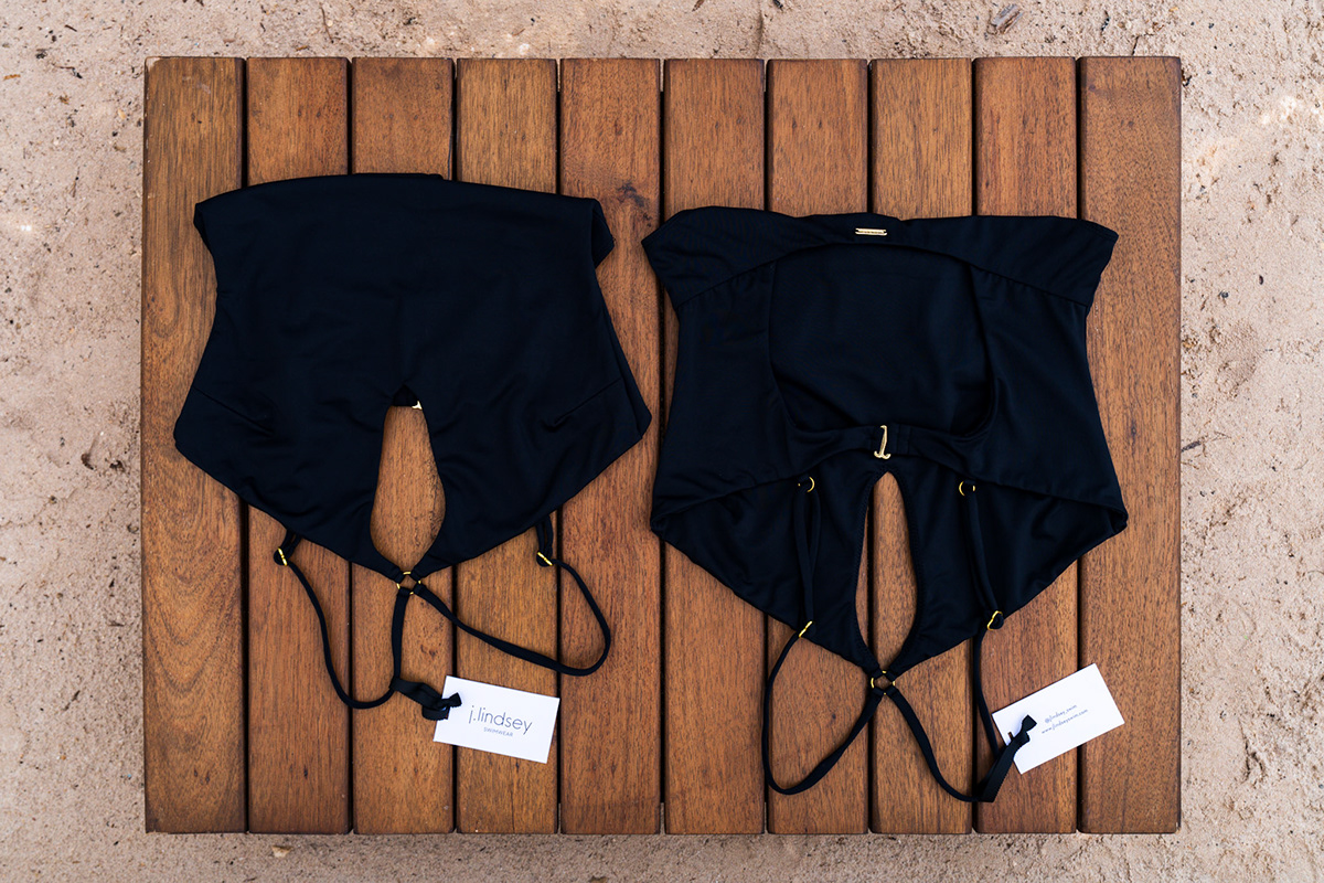 Overhead product photograph of black swimwear on a wooden table — Balabambas Beach Club