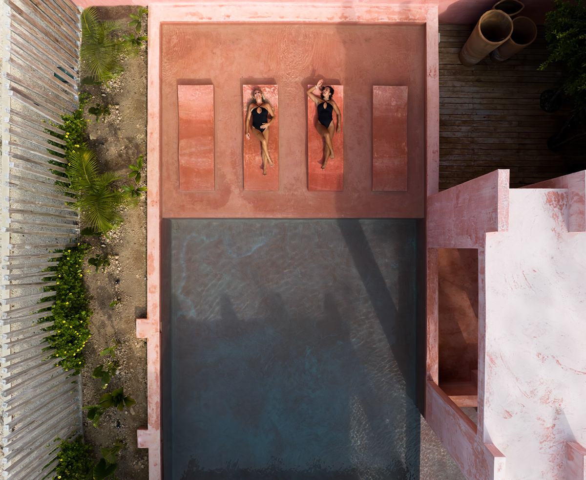 Overhead view of the pink courtyard, swimming pool, and sun loungers — Casa Nikte