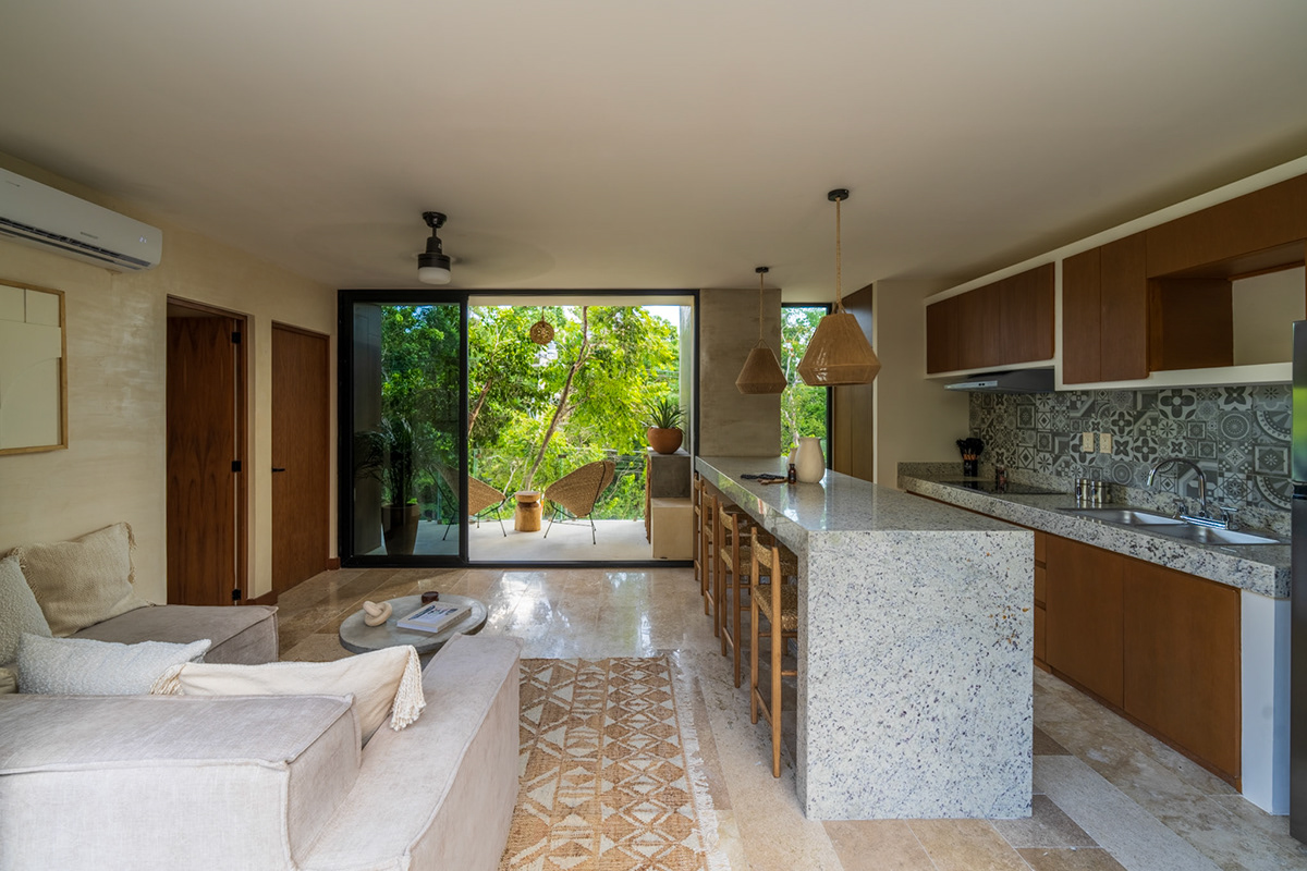 Open-plan living room and kitchen facing a garden window — Casa Noil 27
