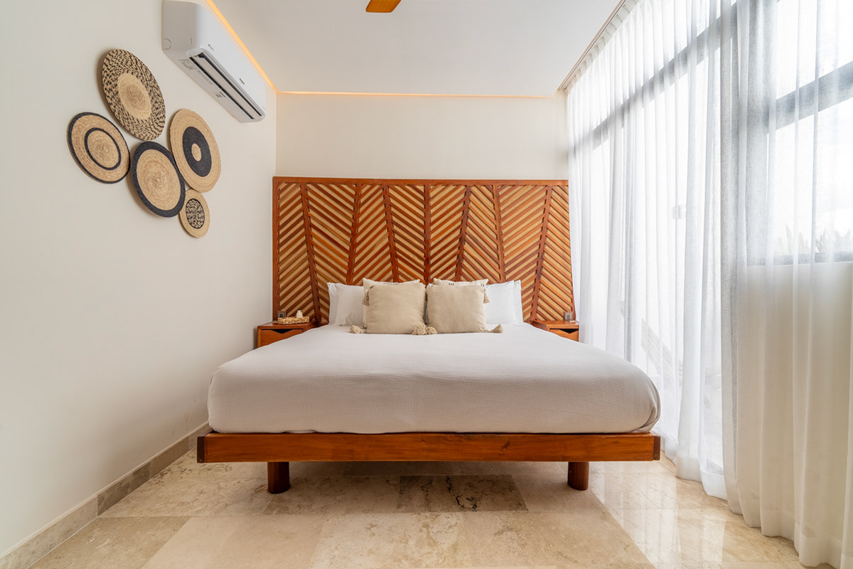Bedroom with a patterned wooden headboard and warm natural light — Elena