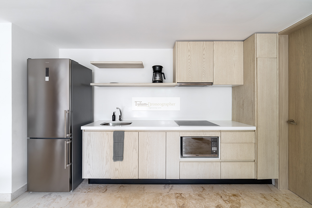 Pale wood kitchen with a refrigerator and built-in appliances — Hunab Residences