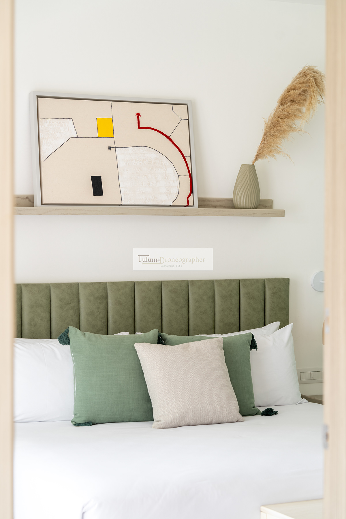 Bedroom detail with a green upholstered headboard and decorative shelf — Hunab Residences