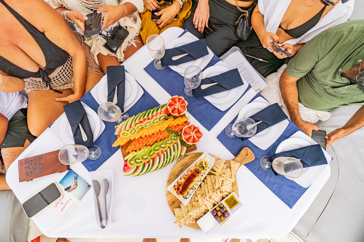 Overhead view of guests sharing a colorful meal on the yacht — Jungle Luxe Yacht