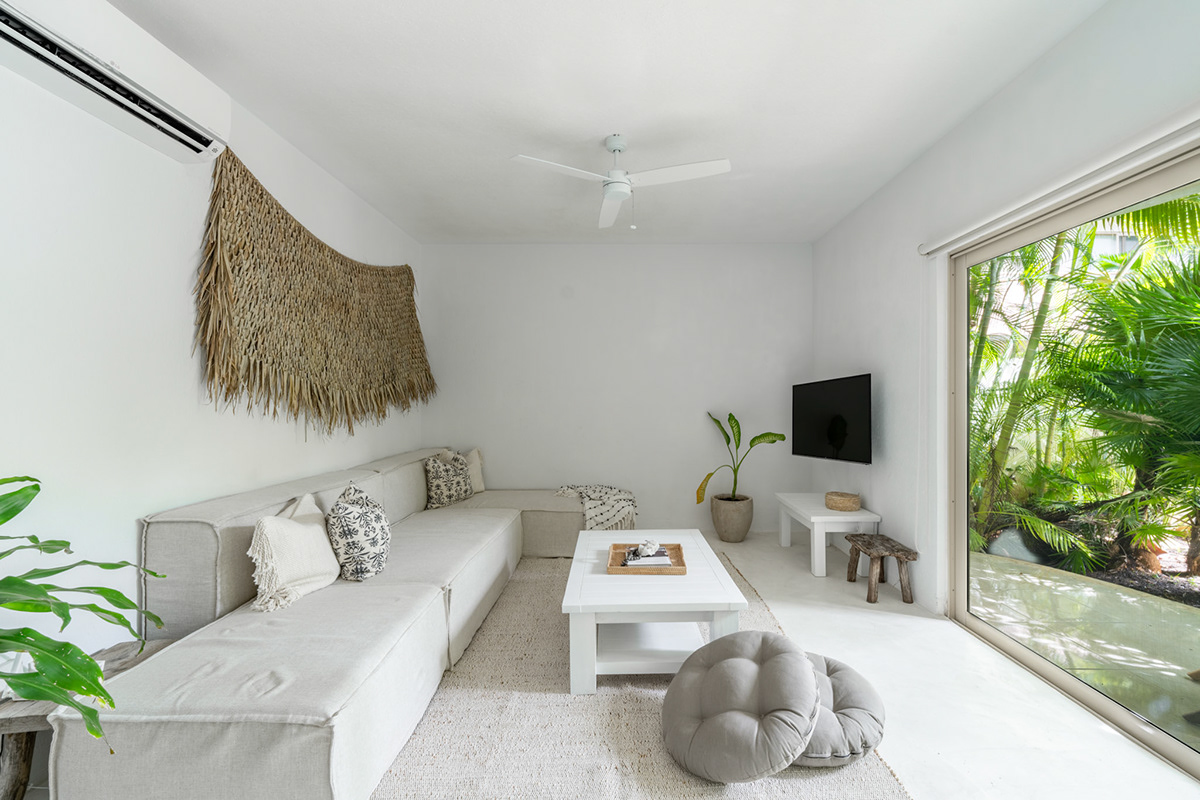 Bright living room with a white sectional and garden windows — Real Zama