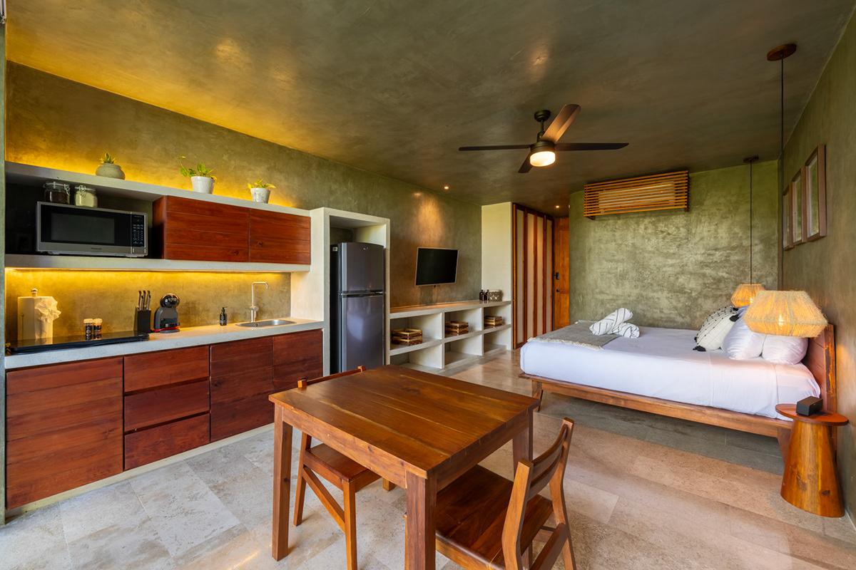 Warm studio interior with kitchen, dining table, and bed — Seremonia Origen