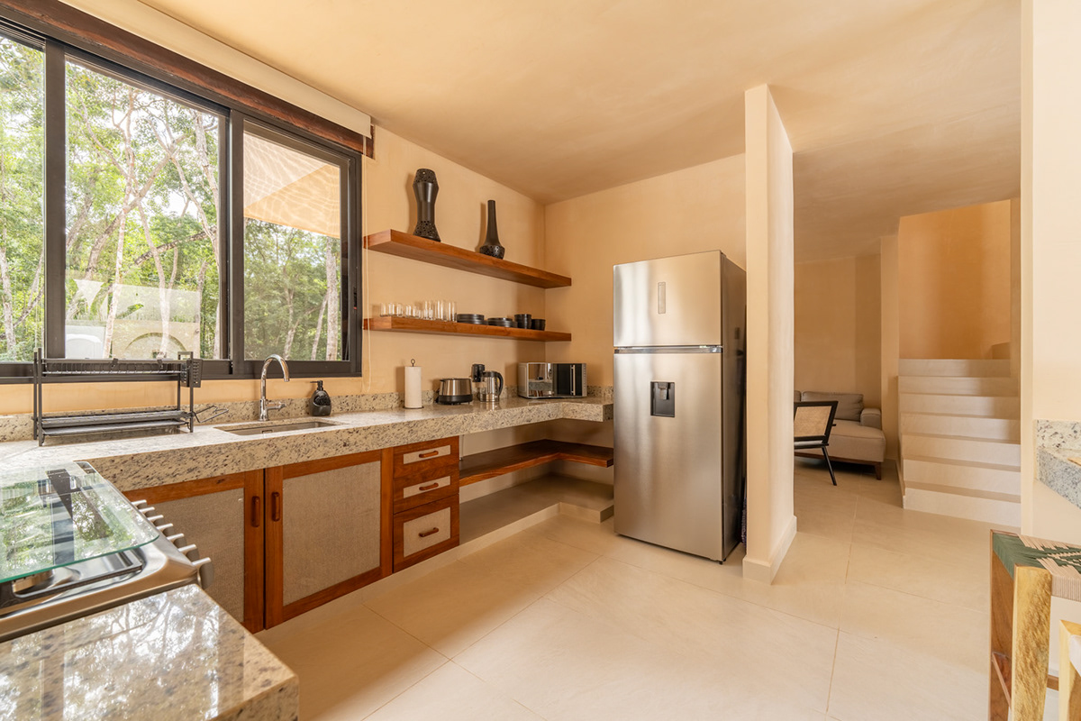Kitchen with wood cabinetry, open shelving, and a view to the garden — Surenna 21
